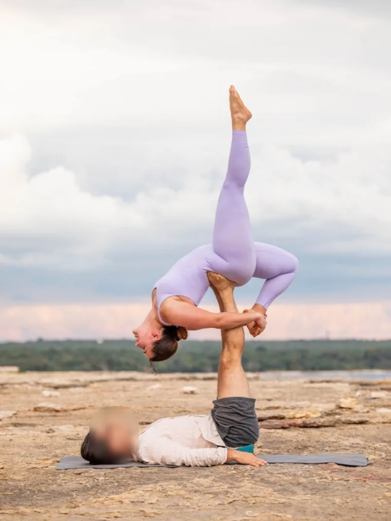 Eleni balancing in an acro yoga flying pose, supported by a training partner